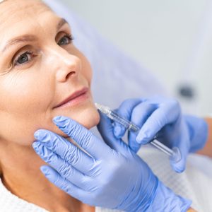 Close up portrait of a dreamy mature woman receiving a beauty injection in her bottom lip